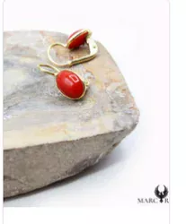 Boucles d’oreilles corail posées sur pierre claire